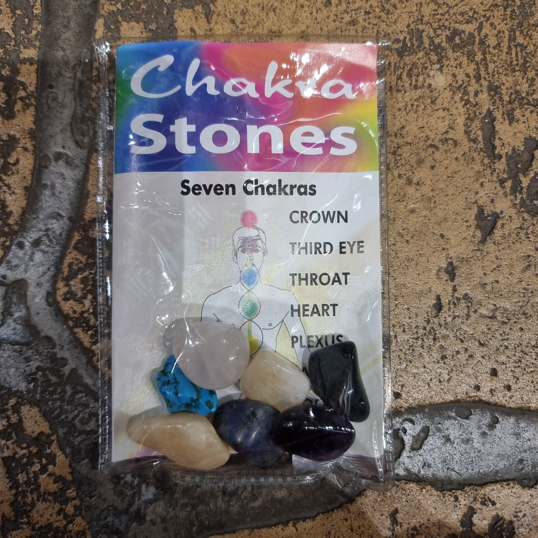 A set of seven tumbled chakra stones arranged in a row from red to violet