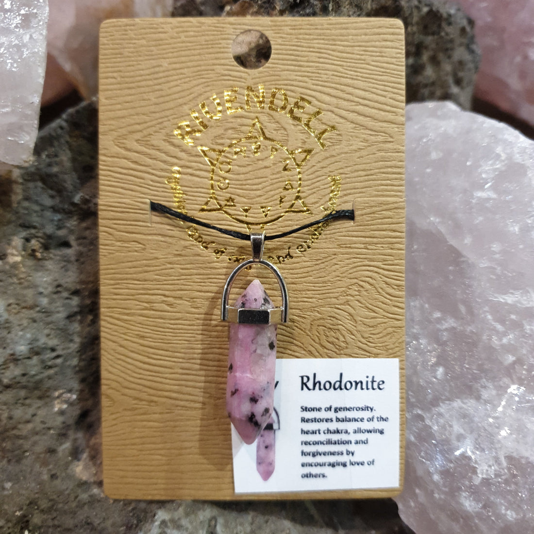 Rhodonite point pendant on a black cord, pinned to a gold Rivendell card beside rose quartz