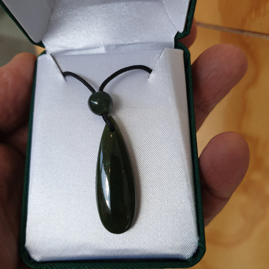 Dark green teardrop pendant with round cord bead in an open green gift box held in a hand