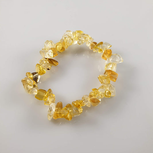 A golden citrine chip bracelet lying on a pale surface