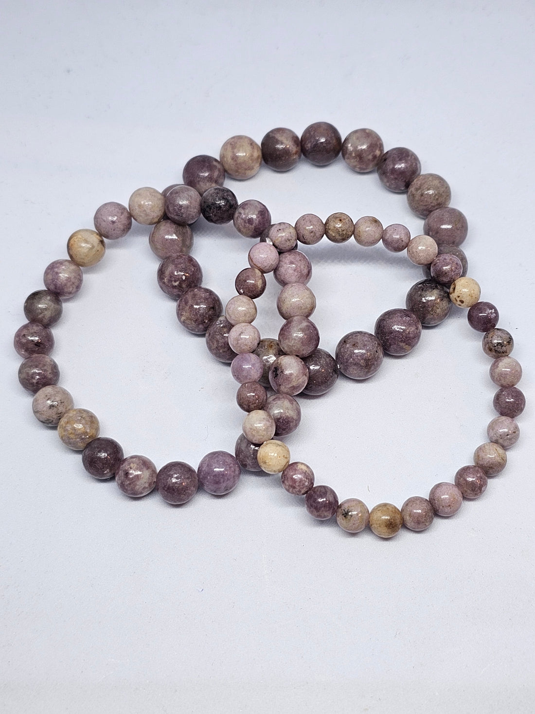 Pale violet lepidolite bead bracelets on a white background