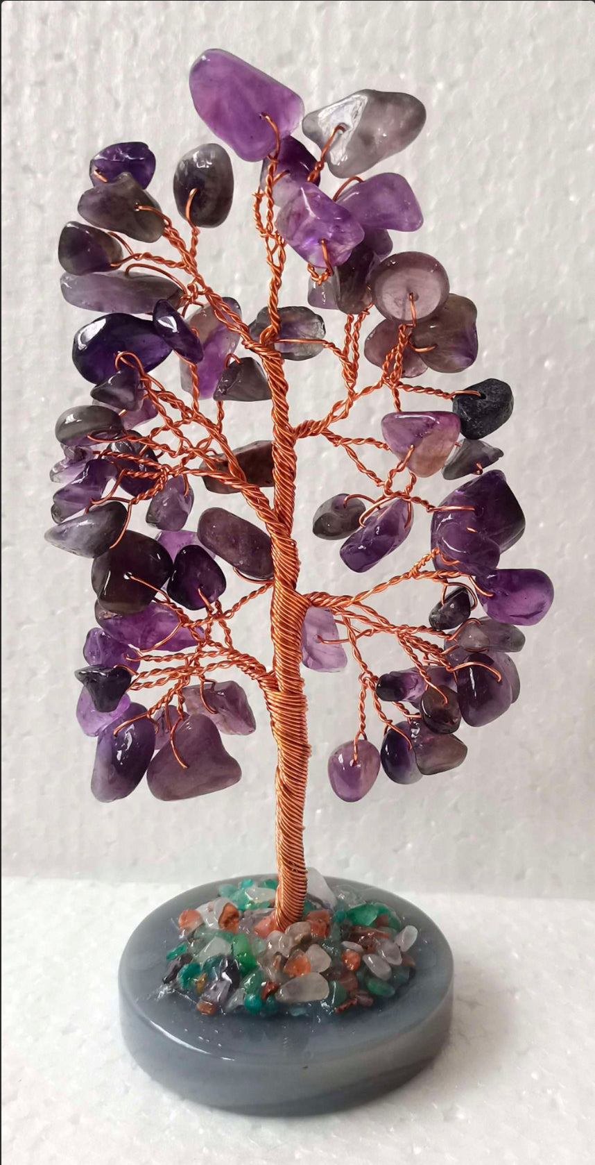 An amethyst crystal tree with violet chips standing on a polished agate base