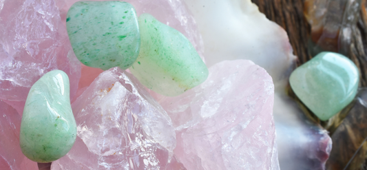 Tumbled green aventurine stones resting among rough pink rose quartz crystals