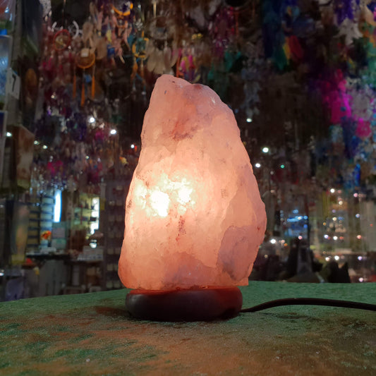 A Himalayan salt lamp glowing deep orange on a shelf in the Rivendell shop.