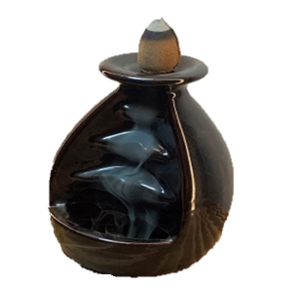 Waterfall backflow incense burner with pale smoke flowing downward over the stone tiers