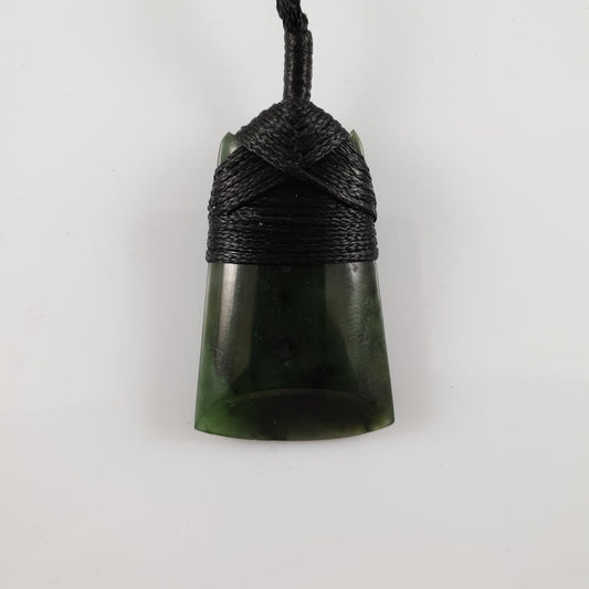 Rectangular greenstone toki pendant on a dark braided cord.
