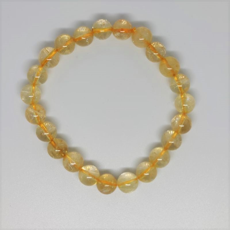 Golden citrine bead bracelet coiled on a pale surface