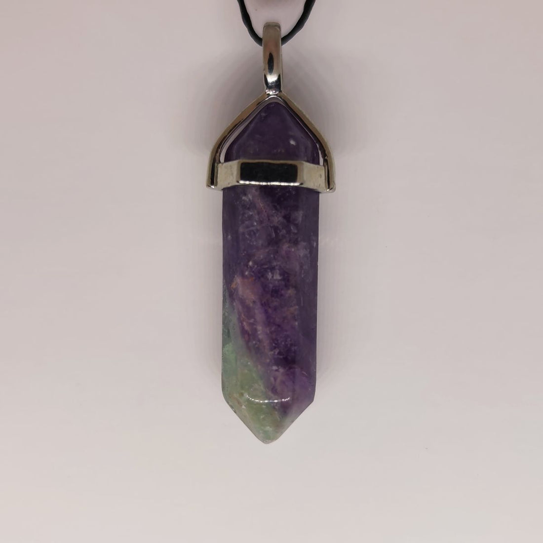 A fluorite crystal point pendant showing soft green and purple bands, a classic study and focus stone