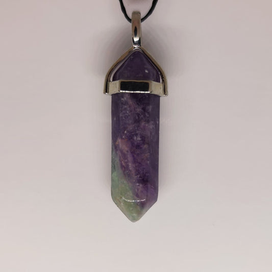 A fluorite crystal point pendant showing soft green and purple bands, a classic study and focus stone