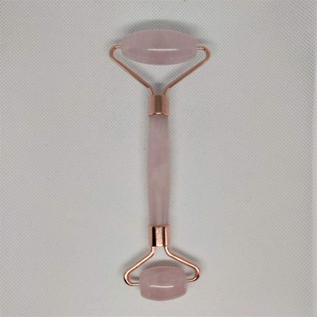 Rose quartz crystal face roller with two smooth pink stone ends