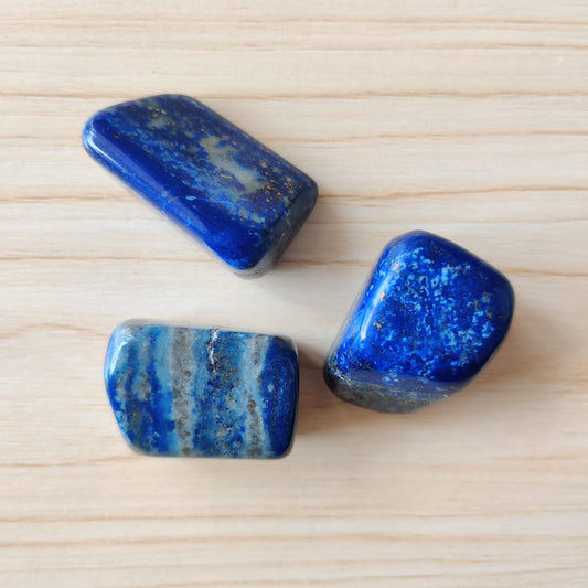 Tumbled lapis lazuli crystals showing deep blue colour with gold pyrite flecks