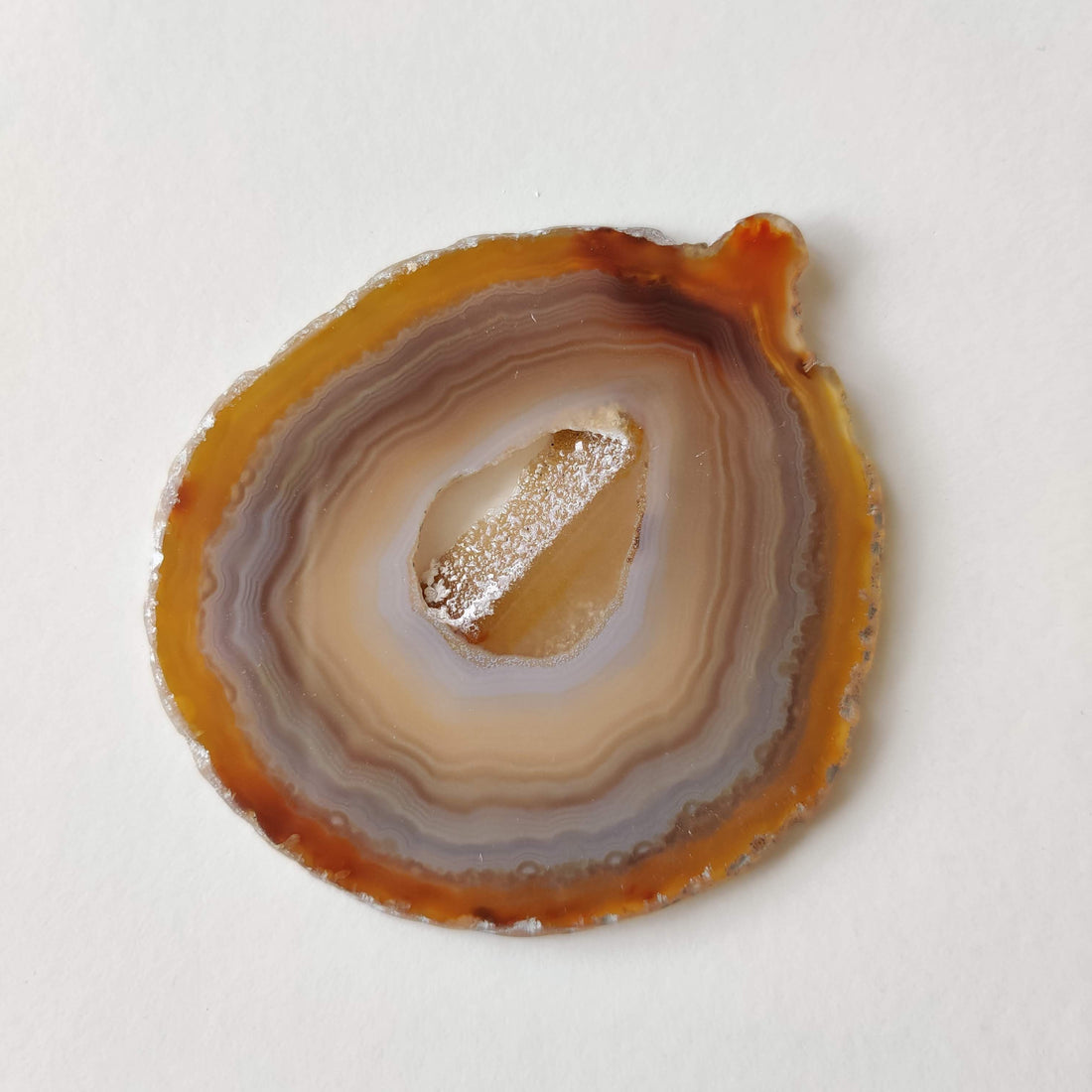 A natural light agate slice showing translucent cream, grey and brown bands