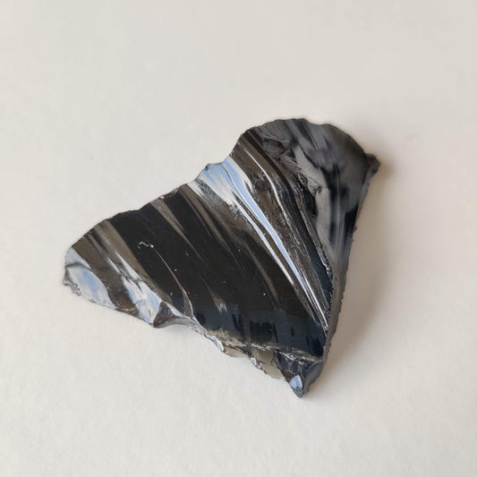 A glossy black obsidian piece with a smooth, glassy volcanic surface
