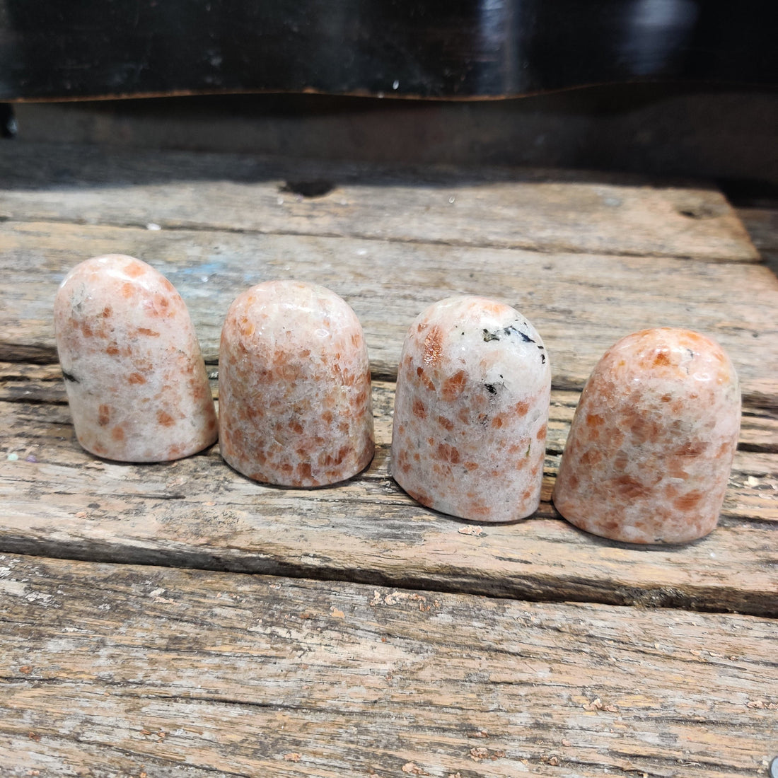 Warm peach sunstone crystals on rustic wood, evoking a sun water ritual