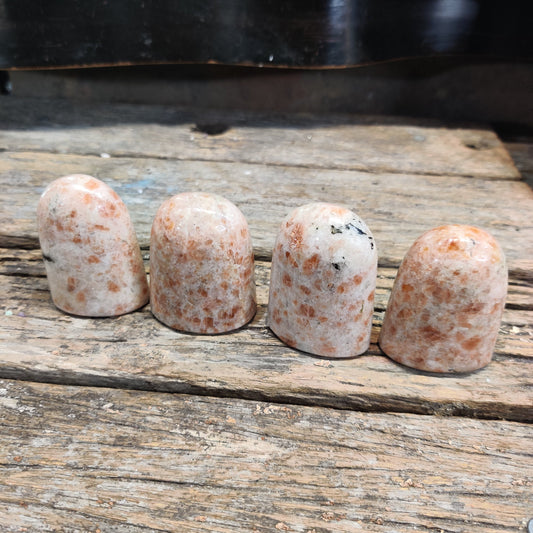 Warm peach sunstone crystals on rustic wood, evoking a sun water ritual