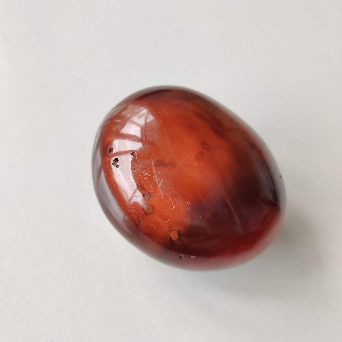Polished carnelian palm stone showing warm orange and deep red banding