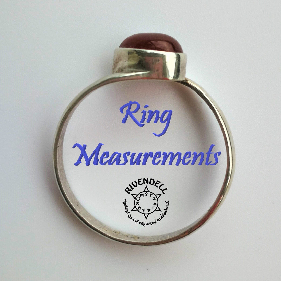 Sterling silver ring with a dark red cabochon stone standing on a white surface, with the words Ring Measurements inside the band
