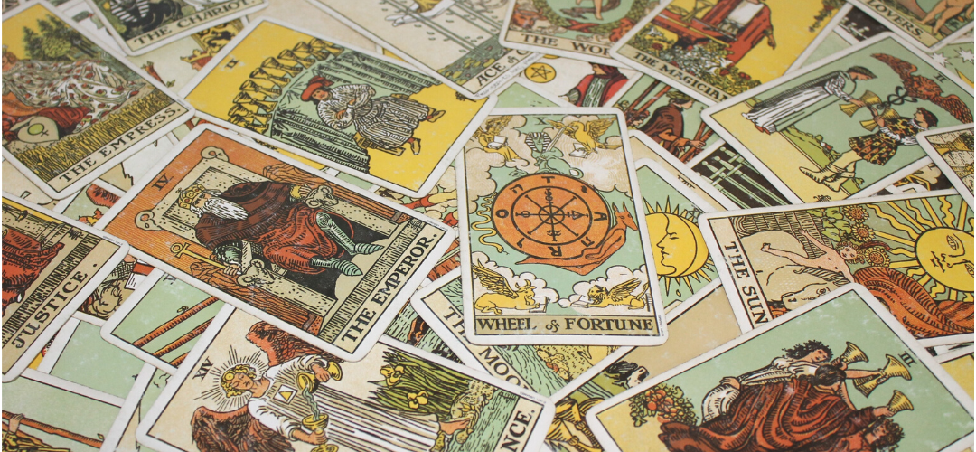 Rider-Waite-Smith tarot cards spread face up on a table, with the Wheel of Fortune, the Emperor and the Sun showing