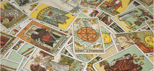 Rider-Waite-Smith tarot cards spread face up on a table, with the Wheel of Fortune, the Emperor and the Sun showing