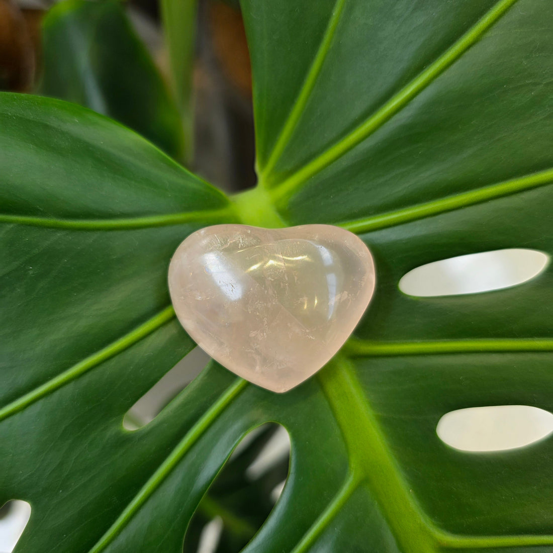 A polished rose quartz heart resting beside its soft drawstring pouch