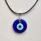 Cobalt-blue glass evil eye pendant on a black waxed cord