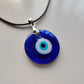 Blue glass nazar necklace viewed at an angle on a white background